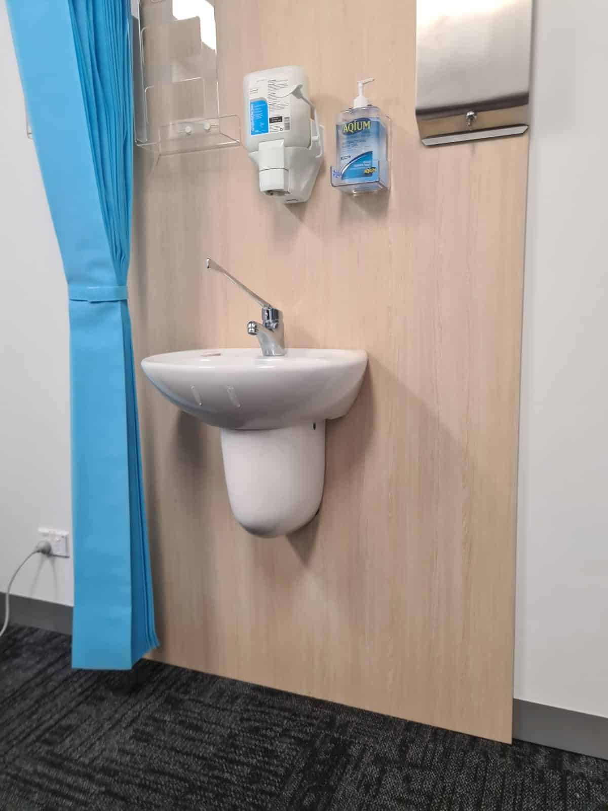 Wall-mounted hand basin and hygiene fittings in a medical treatment room